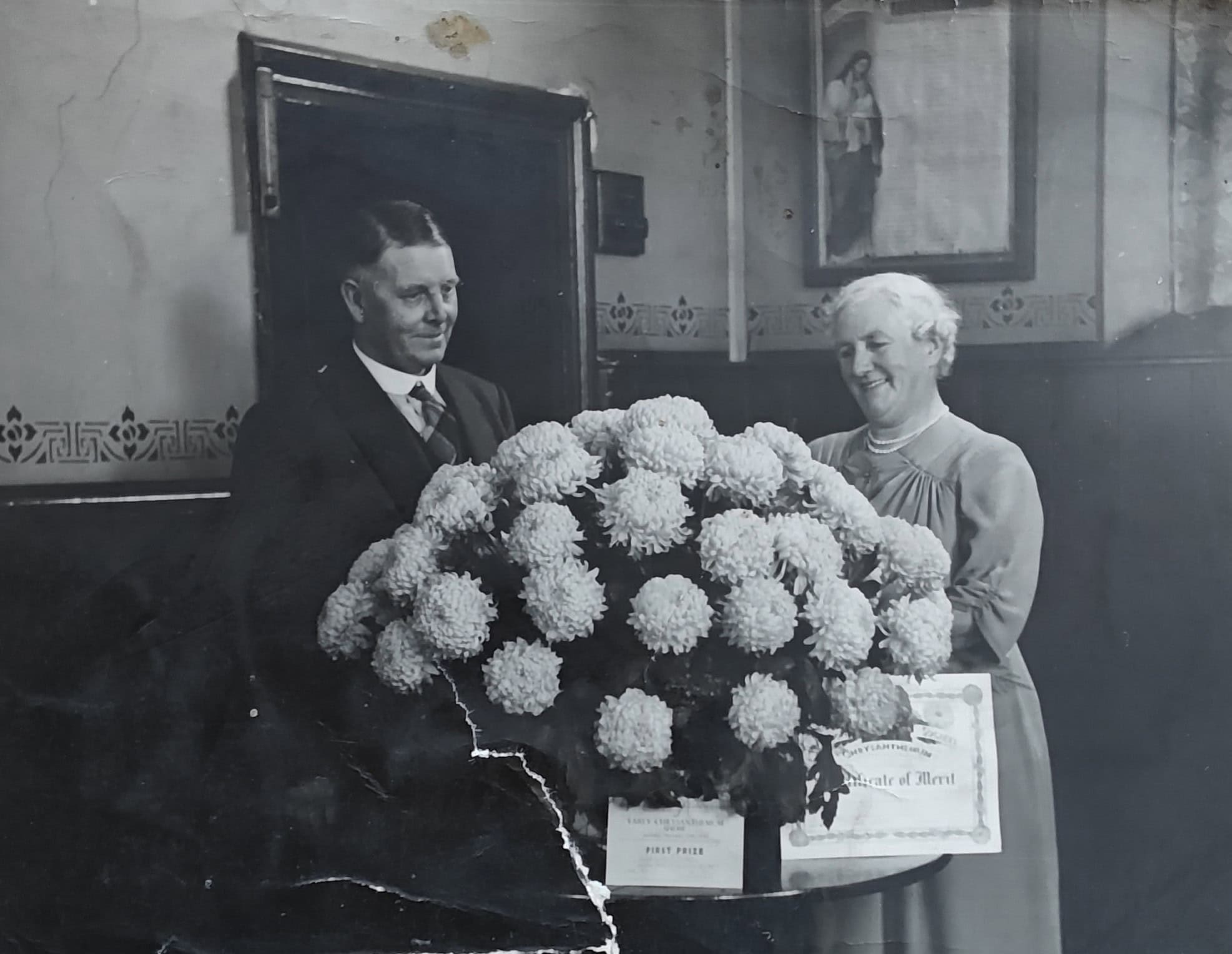 Vintage black and white photo of man and woman with large flower arrangement.